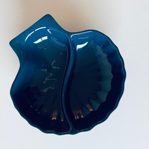 May include: A blue ceramic dish shaped like a seashell with two divided sections.