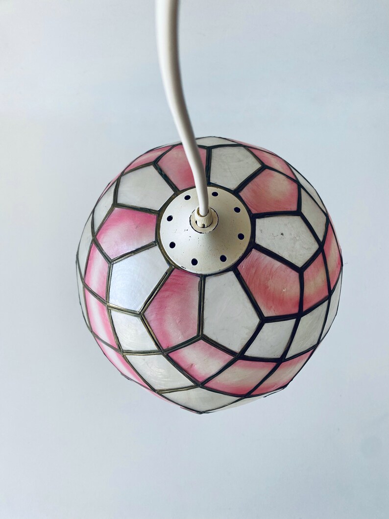 Puede incluir: Una l&aacute;mpara colgante geom&eacute;trica rosa y blanca con un cable blanco. La l&aacute;mpara est&aacute; hecha de un material transl&uacute;cido y tiene un patr&oacute;n geom&eacute;trico.