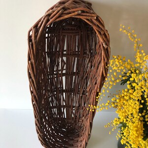 Puede incluir: Una cesta de mimbre marr&oacute;n de forma ovalada alargada. La cesta est&aacute; hecha de mimbre tejido y tiene un aspecto r&uacute;stico y natural.