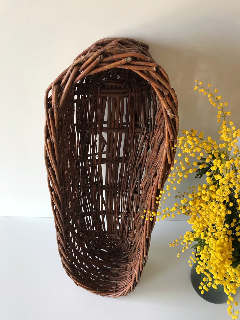 Puede incluir: Una cesta de mimbre marr&oacute;n de forma ovalada alargada. La cesta est&aacute; hecha de mimbre tejido y tiene un aspecto r&uacute;stico y natural.