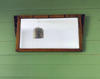 May include: A rectangular wooden framed mirror with a simple design. The mirror is hanging on a green wall.