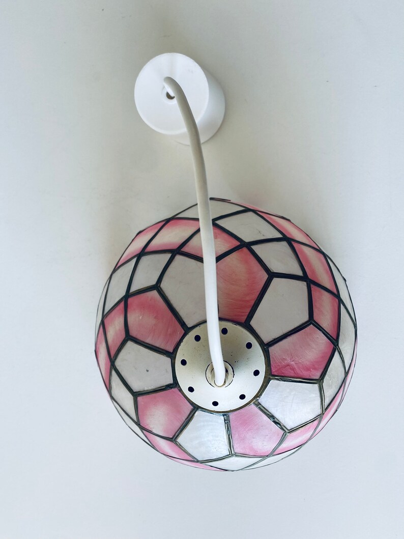 Puede incluir: Una l&aacute;mpara colgante de cristal de colores rosa y blanco con un cable blanco y una montura de techo.