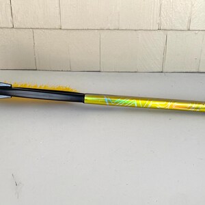 May include: A black and yellow ice scraper with a long, patterned handle. The scraper has a black blade with a hole and a yellow brush. The handle is yellow with a green and blue design.