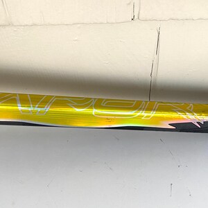 May include: A hockey stick with a yellow and black design. The stick has the word "VAPOR" printed in white. The handle has a black and white strap.