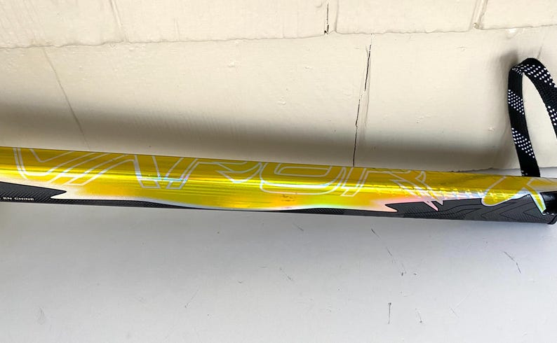 May include: A hockey stick with a yellow and black design. The stick has the word "VAPOR" printed in white. The handle has a black and white strap.