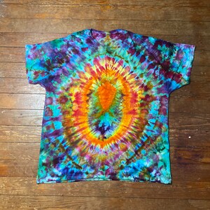May include: A tie-dye t-shirt with a circular pattern in shades of blue, green, orange, red, and purple.
