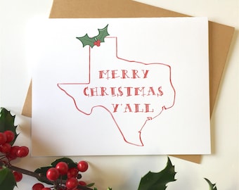 May include: A white card with a red outline of the state of Texas. The outline is decorated with a green holly sprig with red berries. The text "Merry Christmas Y'all" is written in red inside the outline.