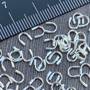 Op de afbeelding: Een close-up van een stapel zilverkleurige metalen springringen. De ringen zijn ongeveer 7 mm in diameter en hebben een gladde, gepolijste afwerking.