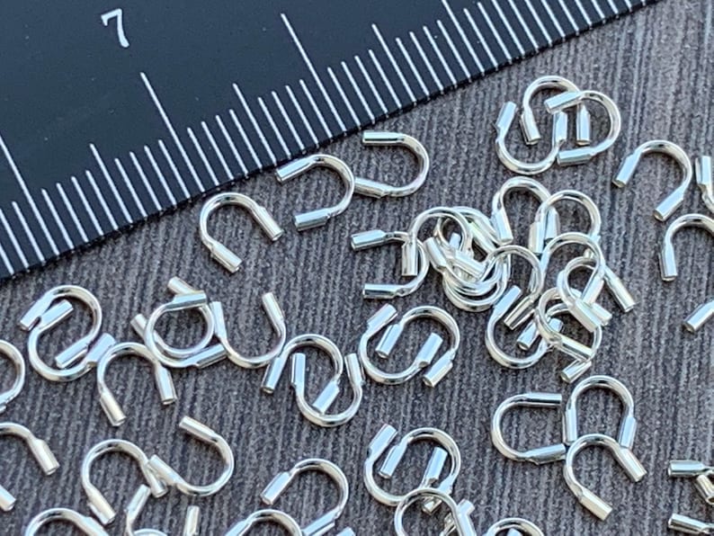 Op de afbeelding: Een close-up van een stapel zilverkleurige metalen springringen. De ringen zijn ongeveer 7 mm in diameter en hebben een gladde, gepolijste afwerking.