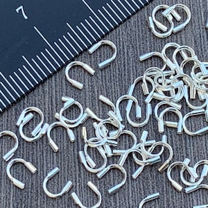 Op de afbeelding: Een close-up van een stapel zilverkleurige springringen. De ringen zijn klein en hebben een afgeronde vorm. Ze zijn perfect voor het maken van sieraden of andere knutselprojecten.
