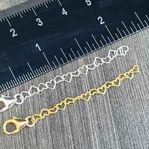 Puede incluir: Dos extensores de cadena en forma de corazón, uno plateado y otro dorado, con cierres de langosta. Las cadenas miden aproximadamente 5 cm de largo.