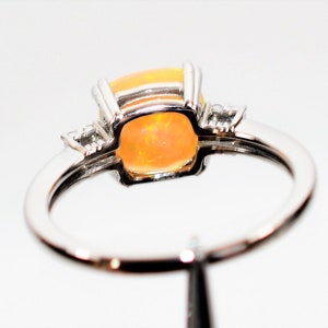 May include: A silver ring with a large orange opal gemstone and two smaller diamond accents.