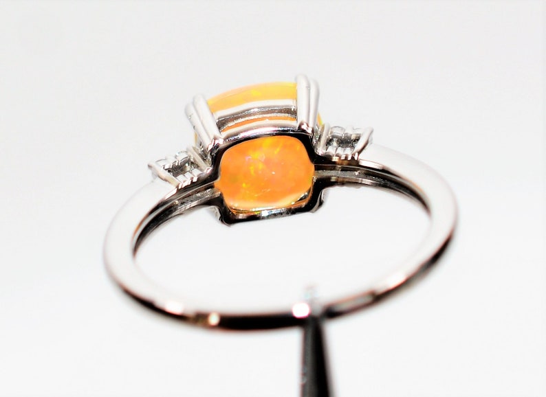 May include: A silver ring with a large orange opal gemstone and two smaller diamond accents.