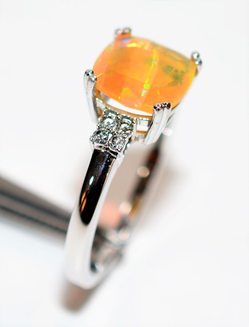 May include: A silver ring with a large, orange opal gemstone and smaller clear gemstones on the band.