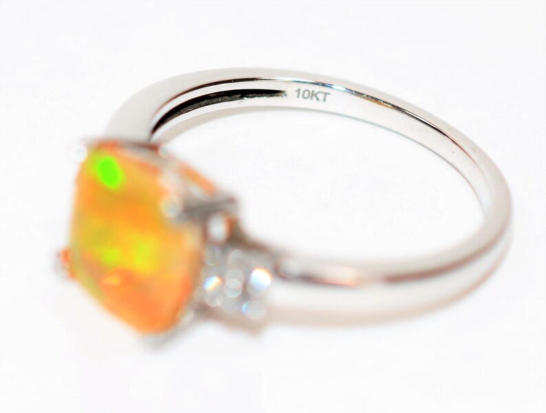 May include: A gold ring with a large orange opal gemstone and smaller diamonds on the band. The ring is marked "10KT" on the inside.