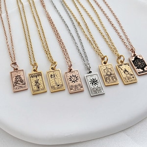 May include: Eight gold, silver, and rose gold necklaces with tarot card pendants. The pendants feature various tarot card imagery, including The Emperor, Hanged Man, The Hermit, The Magician, The Star, The Chariot, The Wheel, and The Sun.