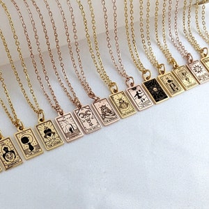 May include: A set of gold necklaces with tarot card pendants. Each pendant features a different tarot card design, including The Tower, The Devil, The Moon, and The Star.