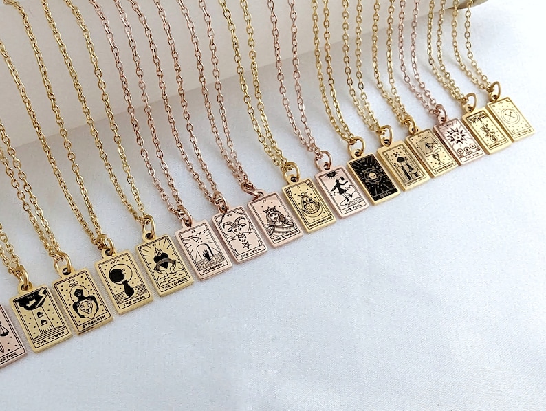 May include: A set of gold necklaces with tarot card pendants. Each pendant features a different tarot card design, including The Tower, The Devil, The Moon, and The Star.