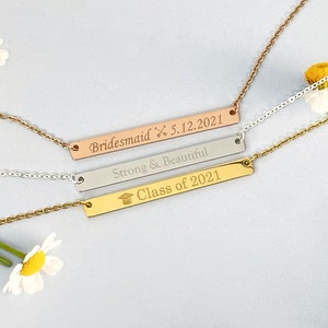 Peut inclure: Trois colliers à barre dorée avec des inscriptions différentes. Le collier du haut dit "Bridemaid 5.12.2021". Le collier du milieu dit "Strong & Beautiful". Le collier du bas dit "Class of 2021" avec une icône de chapeau de graduation.