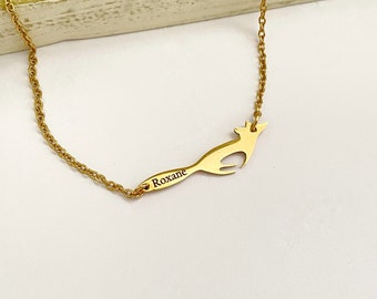 May include: A gold necklace with a fox pendant and a nameplate that says "Roxane".