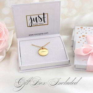 May include: Gold necklace with a round pendant engraved with the name "Madison". The necklace is in a white gift box with the words "just for you" and a website address.
