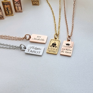 May include: Three gold, silver, and rose gold necklaces with rectangular pendants. The pendants have the words "Holistic Tarot", "By Mathilde", and "Cassandre La Reine du Tarot" engraved on them.