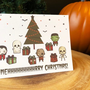 May include: A white Christmas card with a green Christmas tree, a vampire, a ghost, a zombie, a skeleton, and presents. The text on the card reads "MEHhhhhhhHARRY CHRISTMAS!"