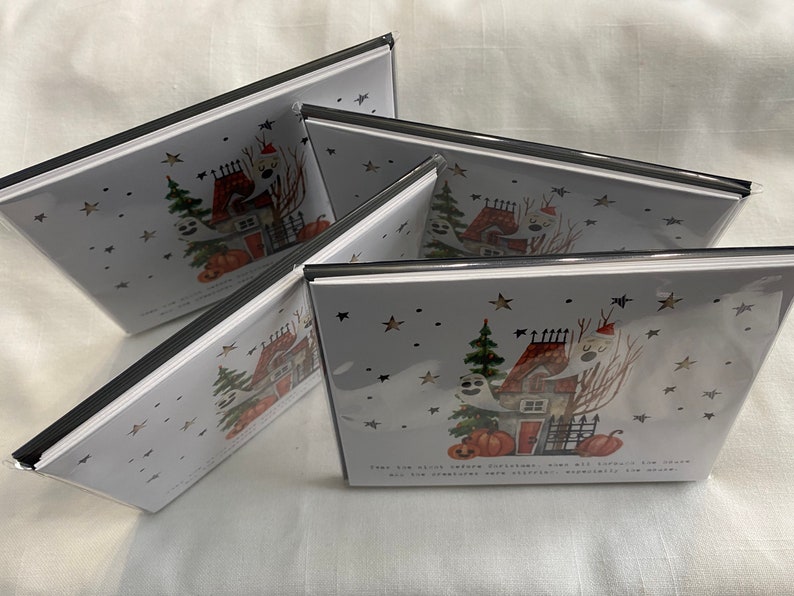 May include: A set of four Halloween greeting cards featuring a spooky house with ghosts, pumpkins, and stars. The text on the card reads "Treats are always better outside, when all the spooky fun is close and the creatures are easily accessible at the door."