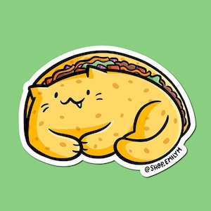 May include: A cartoon illustration of a yellow cat shaped like a taco. The cat has a happy expression and is lying on its side. The taco is filled with meat, lettuce, and cheese. The text '@shop.emilym' is at the bottom right corner of the image.