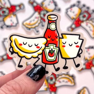 Puede incluir: Una pegatina con una ilustración de dibujos animados de una botella de ketchup, un pierogi y un alimento con forma de Pensilvania. Los tres elementos tienen caras sonrientes y se toman de la mano. La pegatina está sobre un fondo blanco.