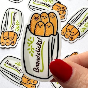 May include: A collection of stickers featuring cartoon breadsticks in a white paper bag. The breadsticks have smiling faces. The bag is labeled "Breadsticks!" in a whimsical font with green accents. The stickers are on a white background.