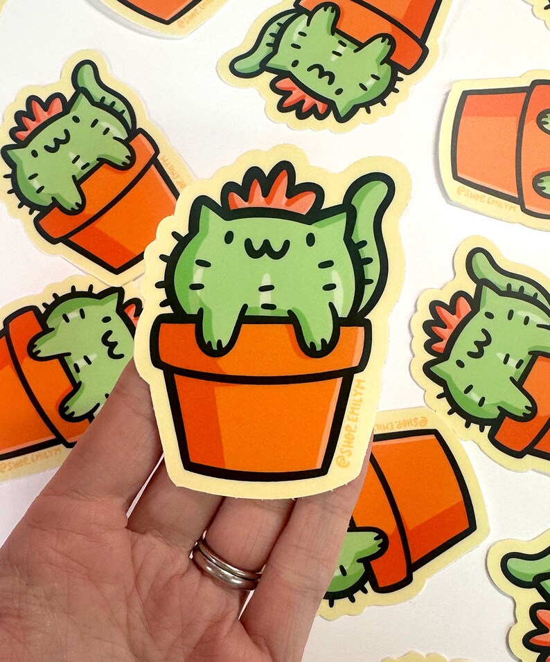 May include: A set of five stickers featuring a green cat with a red flower on its head sitting in a terracotta pot. The cat is depicted as a cactus plant. The stickers are on a white background.