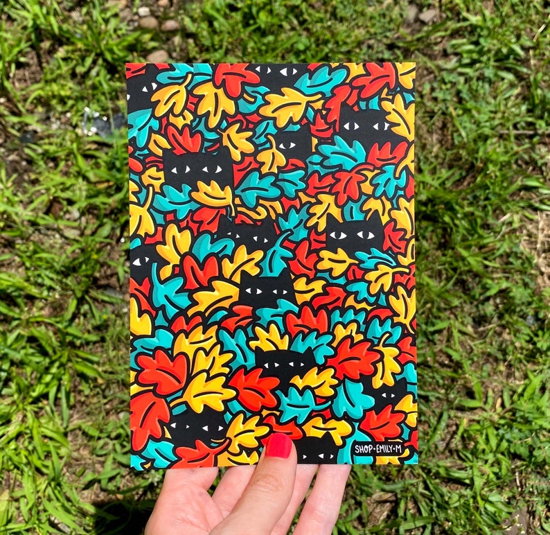May include: A colorful print featuring black cats hidden among a pattern of blue, red, yellow, and green leaves. The print includes the text "SHOP-EMILY-M".