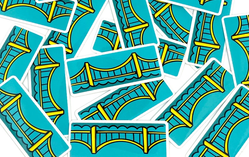 May include: A pile of blue and yellow stickers featuring a cartoon bridge design. The stickers are arranged in a random pattern.
