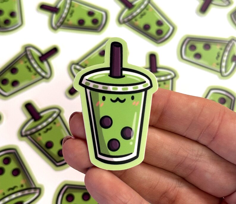 May include: A green and white sticker of a cartoon boba tea cup with a smiling face and black boba pearls. The sticker is on a white background.