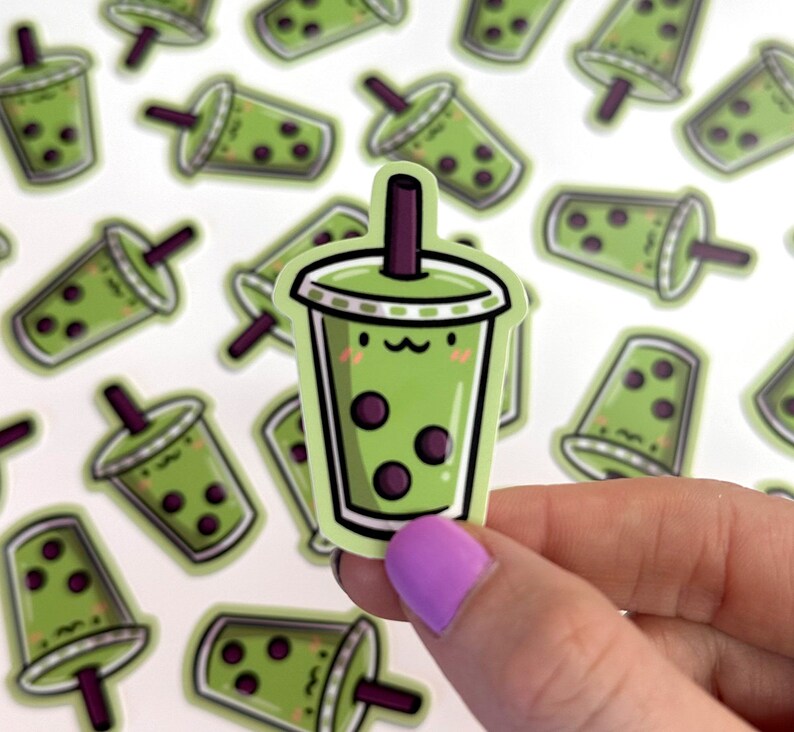 May include: A set of green and purple bubble tea stickers with a cute cartoon face. The stickers are printed on white paper and have a glossy finish.