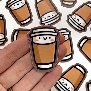 May include: A set of brown and white coffee cup stickers with a cute cartoon face. The stickers have a brown paper cup with a white lid and a white rim. The cartoon face has two black eyes, a small mouth, and two pink cheeks.
