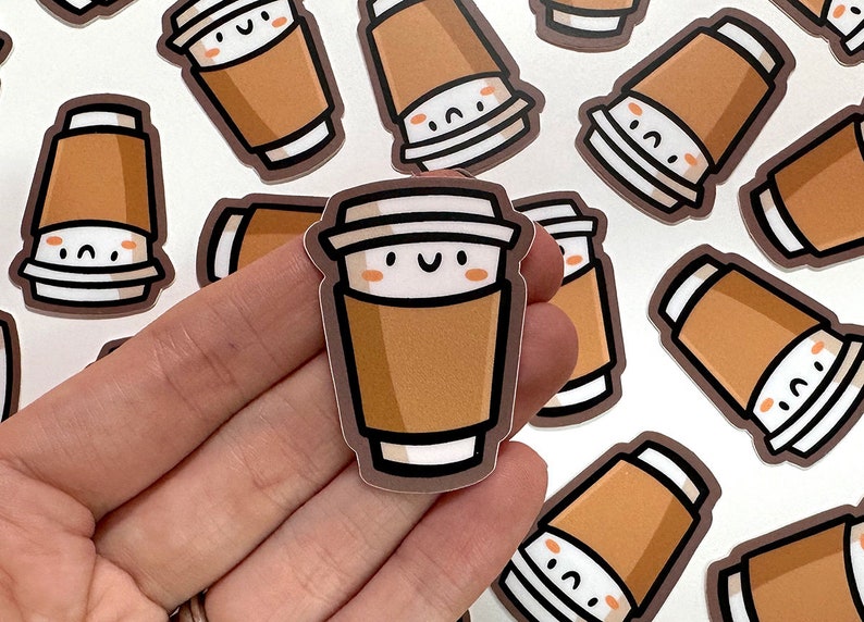 May include: A set of brown and white coffee cup stickers with a cute cartoon face. The stickers have a brown paper cup with a white lid and a white rim. The cartoon face has two black eyes, a small mouth, and two pink cheeks.