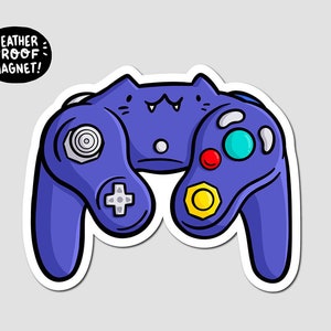 May include: A purple GameCube controller with a cat face on the front. The controller has a white plus sign button, a yellow button, a red button, and a blue button. The text "WEATHER PROOF MAGNET!" is in a white box with a black border.