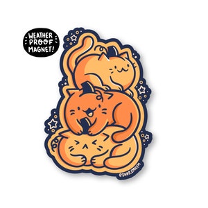 May include: A weatherproof magnet featuring three orange cats stacked on top of each other. The cats are drawn in a cartoon style with black outlines. The magnet has a white background with a blue border and stars. The text "WEATHER PROOF MAGNET!" is written in white on a blue circle at the top of the magnet.
