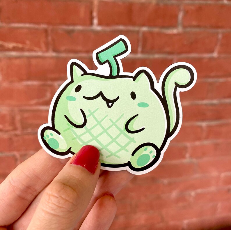 May include: A green and white cartoon cat sticker with a melon-like pattern and a green stem on its head.