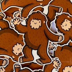 Puede incluir: Una colecci&oacute;n de pegatinas marrones y blancas con ilustraciones de dibujos animados de Bigfoot. Las pegatinas est&aacute;n impresas en papel blanco y tienen un acabado brillante.