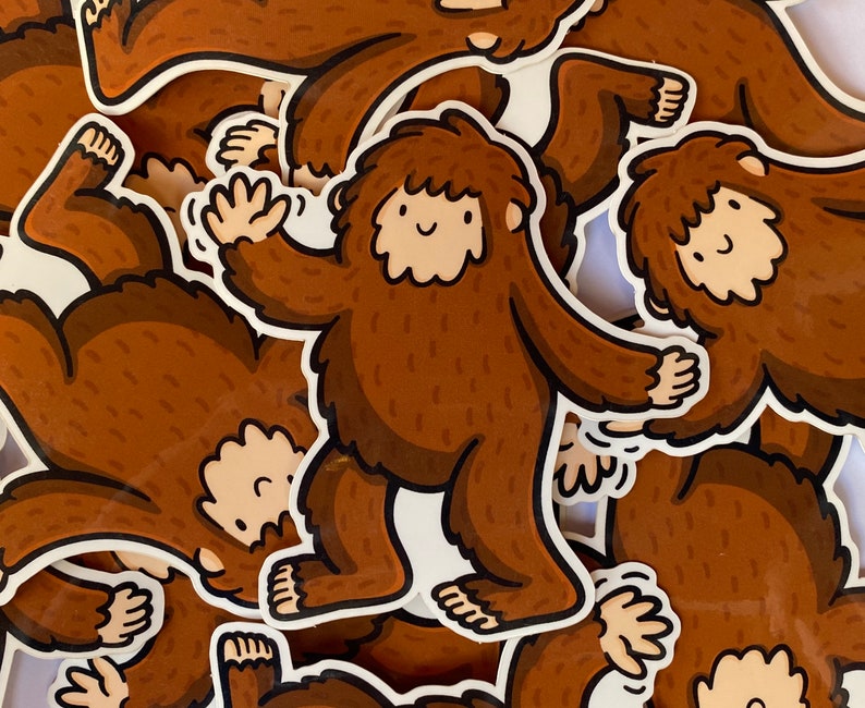 Puede incluir: Una colecci&oacute;n de pegatinas marrones y blancas con ilustraciones de dibujos animados de Bigfoot. Las pegatinas est&aacute;n impresas en papel blanco y tienen un acabado brillante.