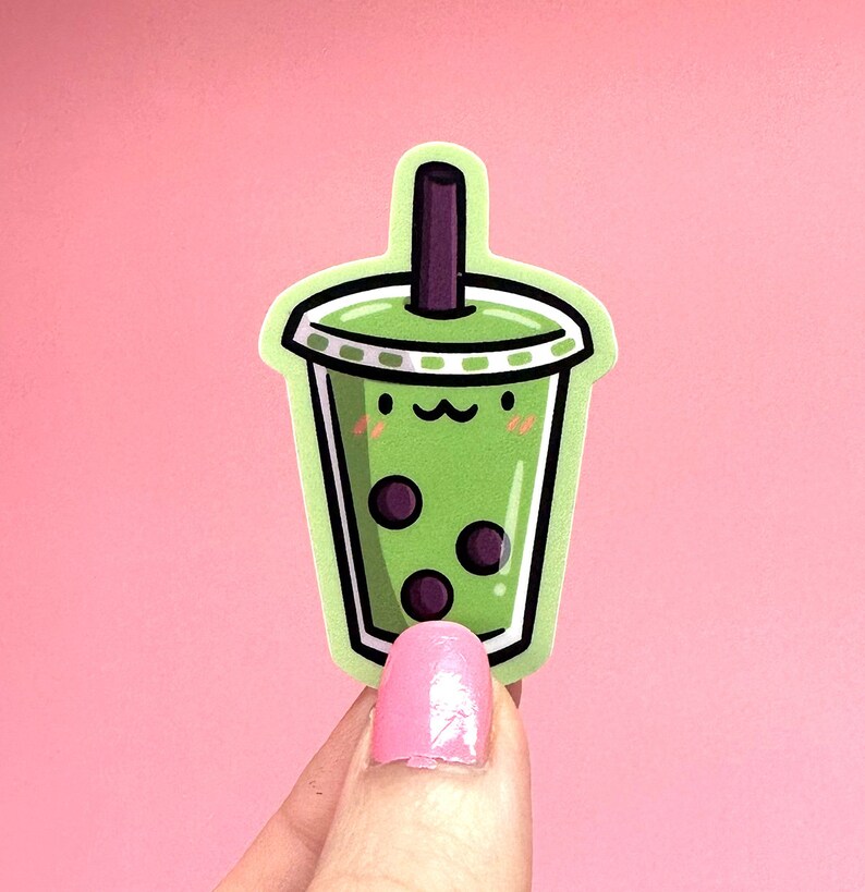 May include: Green and white cartoon bubble tea with black boba pearls and a cute face. The bubble tea is in a clear cup with a green lid and a straw.