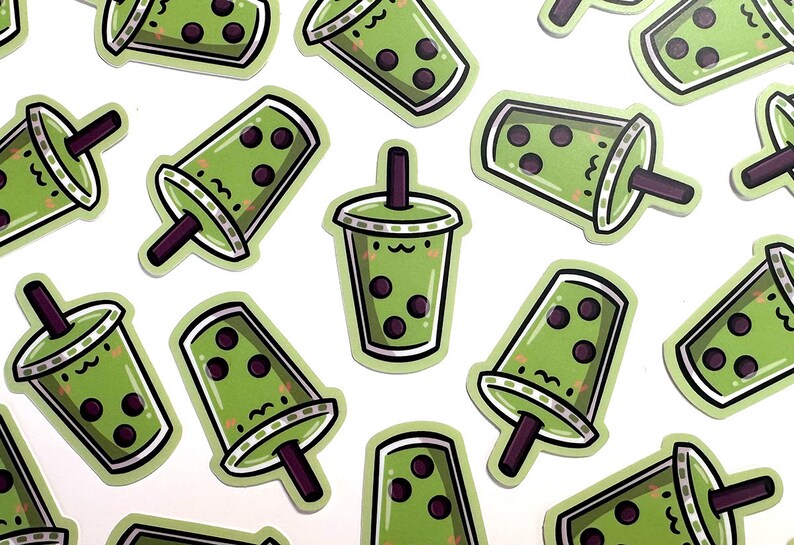 May include: A sheet of green and black bubble tea stickers with a cartoon face and a straw.