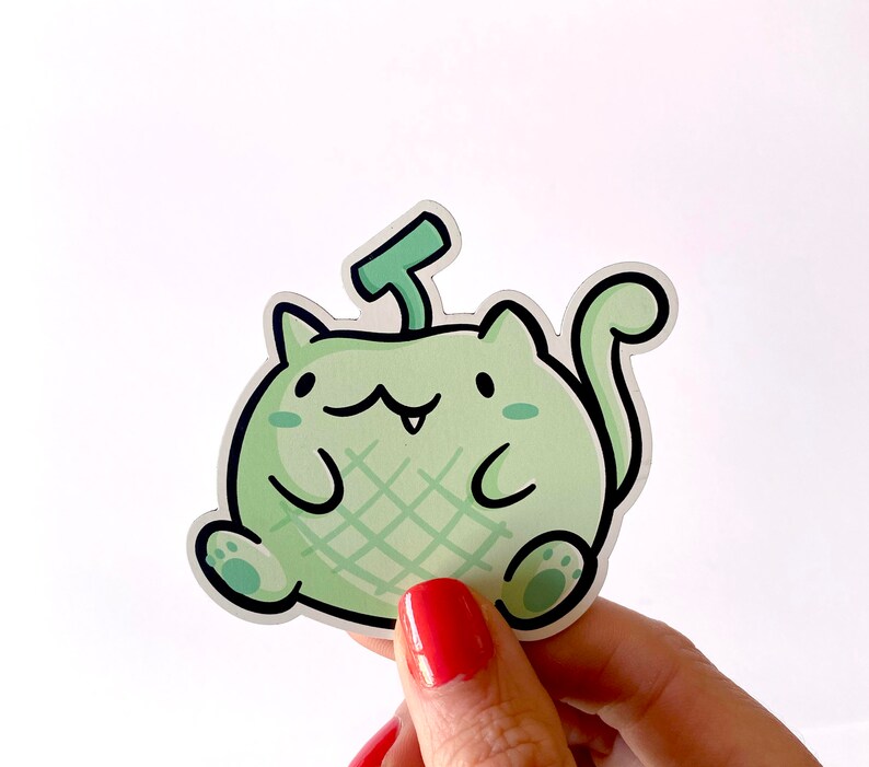 May include: A green and white cartoon cat sticker with a melon-like pattern and a small green stem on its head.