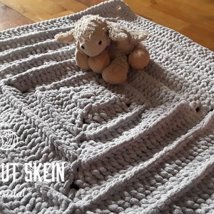 May include: A gray crocheted baby blanket with a textured pattern. The blanket is made with chunky yarn and has a soft, fluffy texture. The blanket is large enough to cover a baby or toddler.