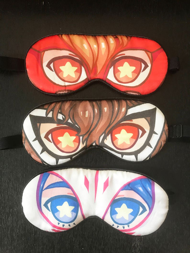 May include: Three sleep masks with different character designs. Each mask has a pair of large eyes with a yellow star in the center. The top mask is red with a brown haired character. The middle mask is brown with a brown haired character. The bottom mask is white with a blue haired character.