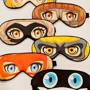 May include: Six colorful sleep masks with different cartoon characters. Each mask has a unique design with large eyes and a black elastic band.
