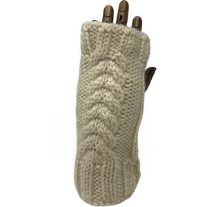 Puede incluir: Guantes sin dedos de punto de color crema con un patrón de trenza.